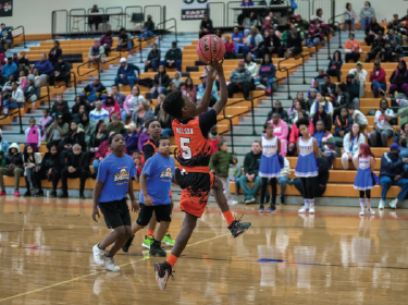 young boy shooting lay up in basketball
